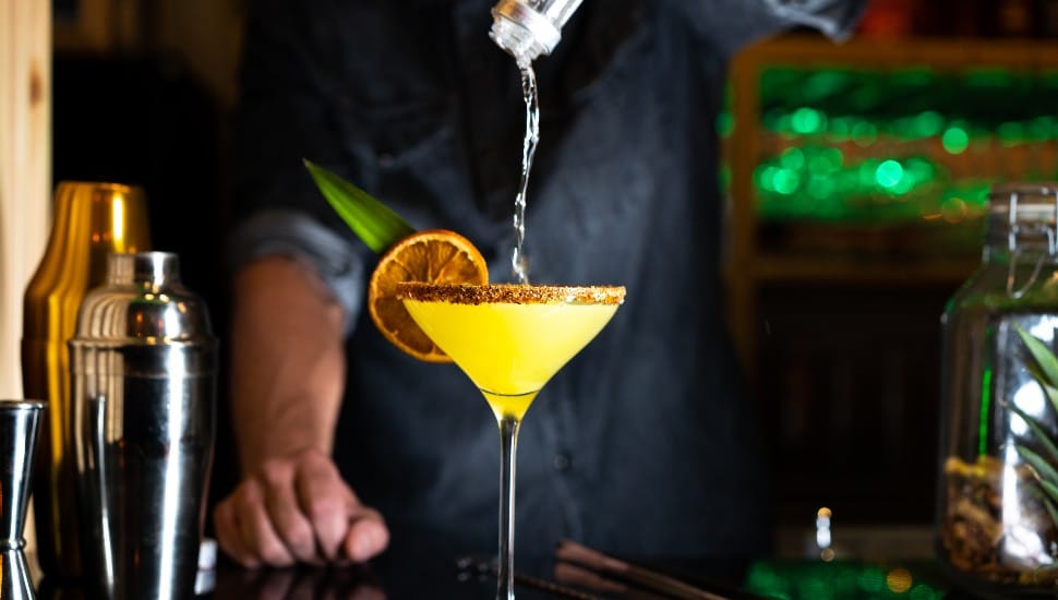 Bartender pouring alcohol on a cocktail in a night club bar. Close-up