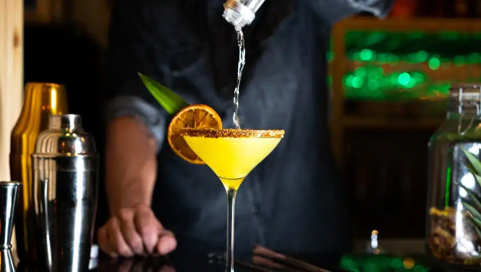 Bartender pouring alcohol on a cocktail in a night club bar. Close-up
