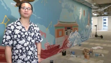 Chenlin Cai in front of mural at 1735 Market Street.