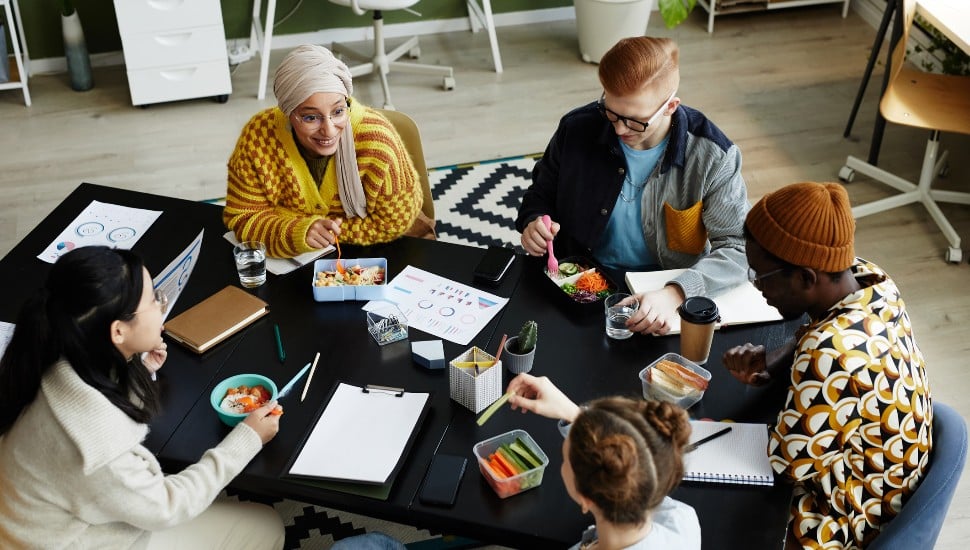 High angle view at diverse creative team at coworking space during lunch