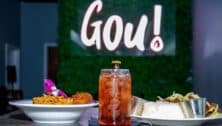 Gou! restaurant in Philly, dishes and drink in front of logo