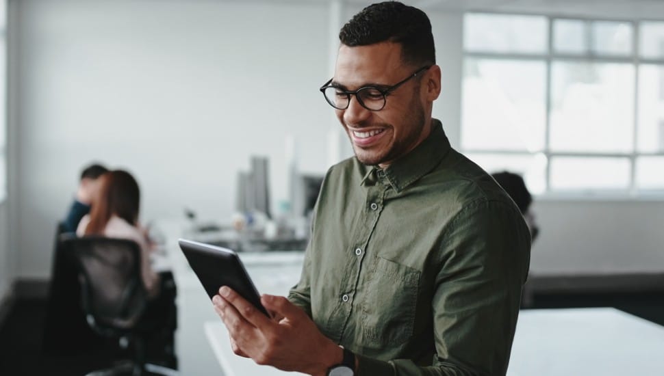 business man holding ipad smiling in office