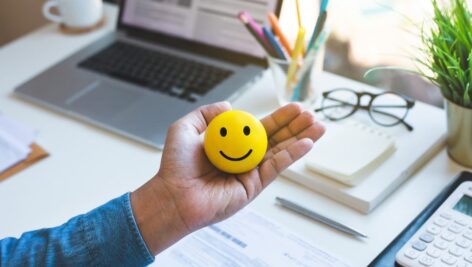 Emoticon ball on male hand on work table.