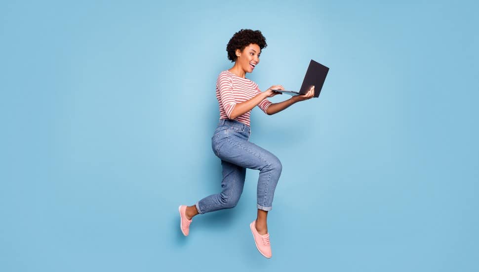 woman jumping mid air with laptop