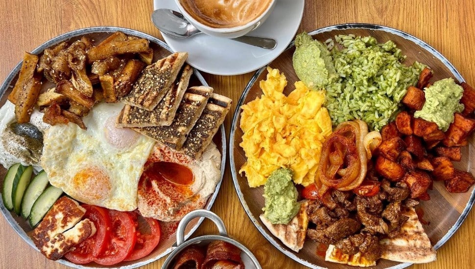 two plates of Lebanese breakfast food with cups of coffee and bacon