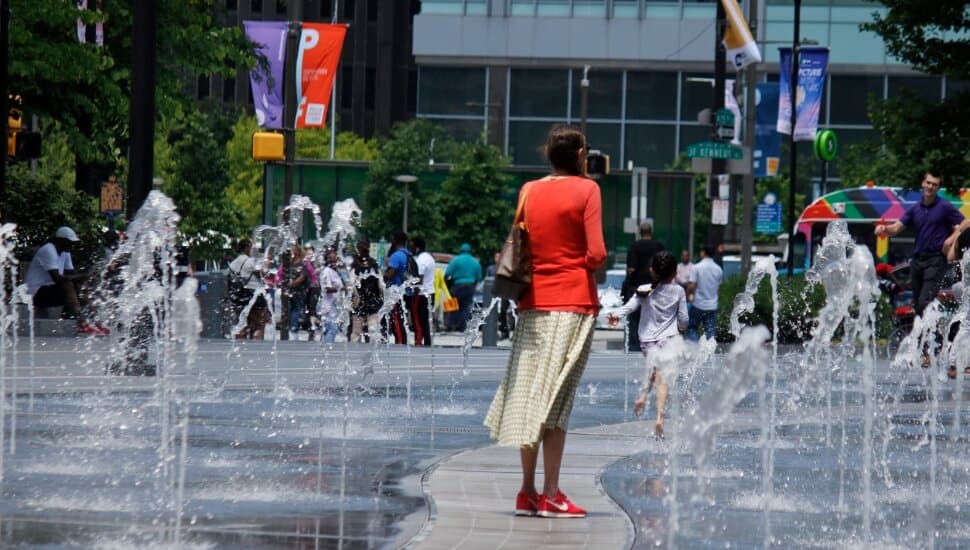 a mother watches her child play in the fountains at Dilworth Plaza.