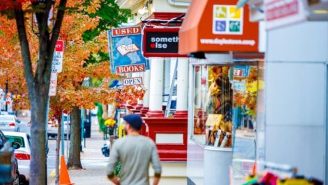 person from behind on doylestown sidewalk with storefronts and tree in autumn