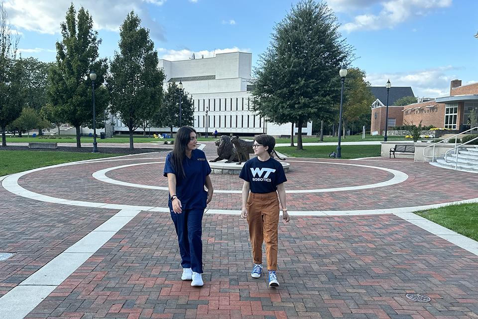 Students Marlaina Pappero and Emma Castellano chat on campus. Image via Widener University.