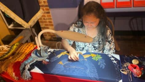 Hand embroiderer from the Defense Logistics Agency (DLA) Troop Support manufacturing a flag.