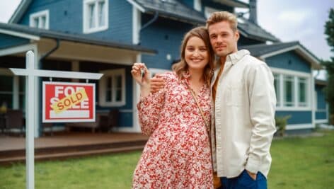 A couple standing in front of their recently purchased home.