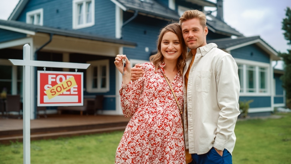 A couple standing in front of their recently purchased home.