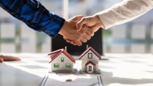 Two people shaking hands of house models.