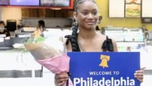 A woman holds a sign welcoming people to the Philadelphia International Airport.