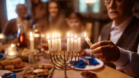 Family celebrating Hanukkah by lighting menorah.