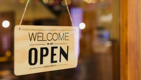 Welcome We're Open Sign Hanging in a small business window