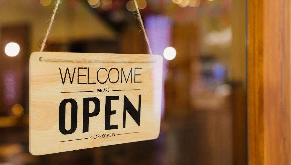 Welcome We're Open Sign Hanging in a small business window