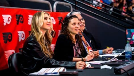 Individuals sitting in a commentary table at a Philadelphia Flyers game.