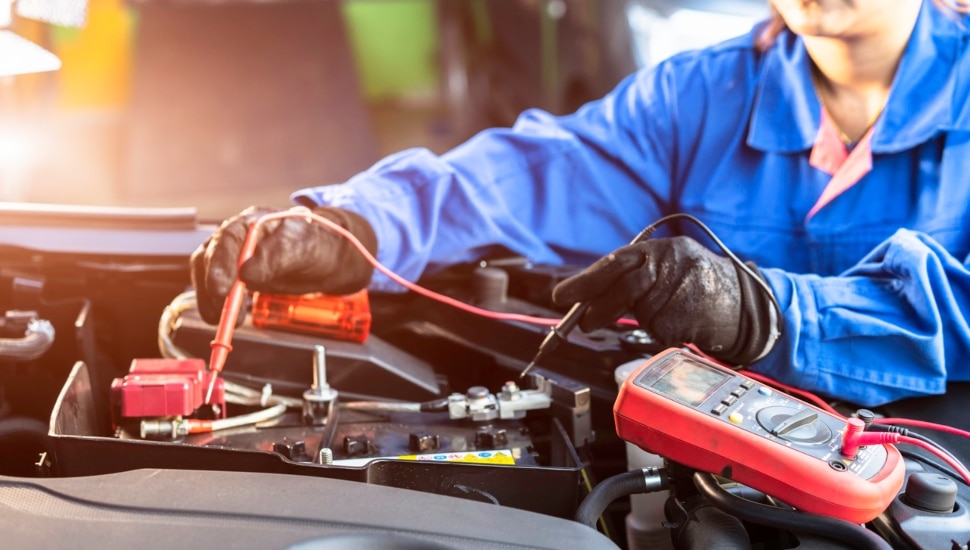 Car technician measures voltage of battery in the car