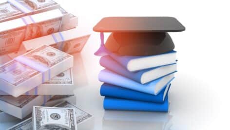 Graduation mortar board cap and books with stack of US dollars