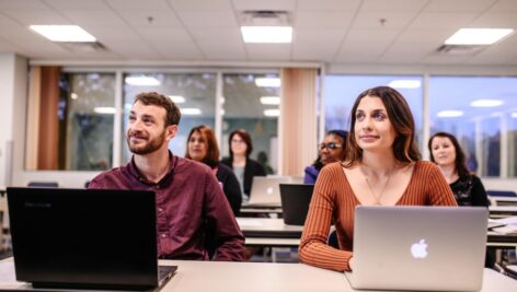 Neumann University students sitting in a classroom in front of laptop computers.