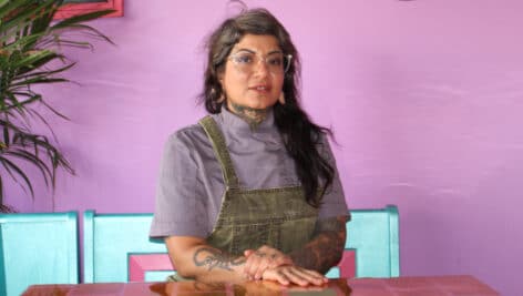 Owner of Juana Tamale sits at table inside her restaurant.