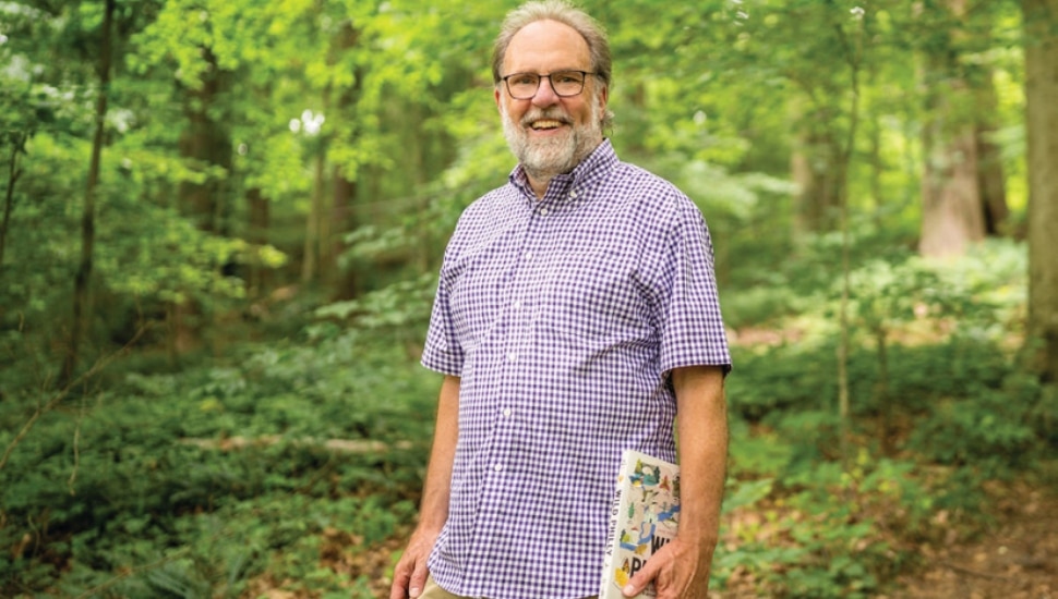 Michael Weilbacher in the forest, holding his new book.