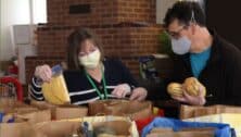 People at Old Pine Community Center placing groceries in a bag.