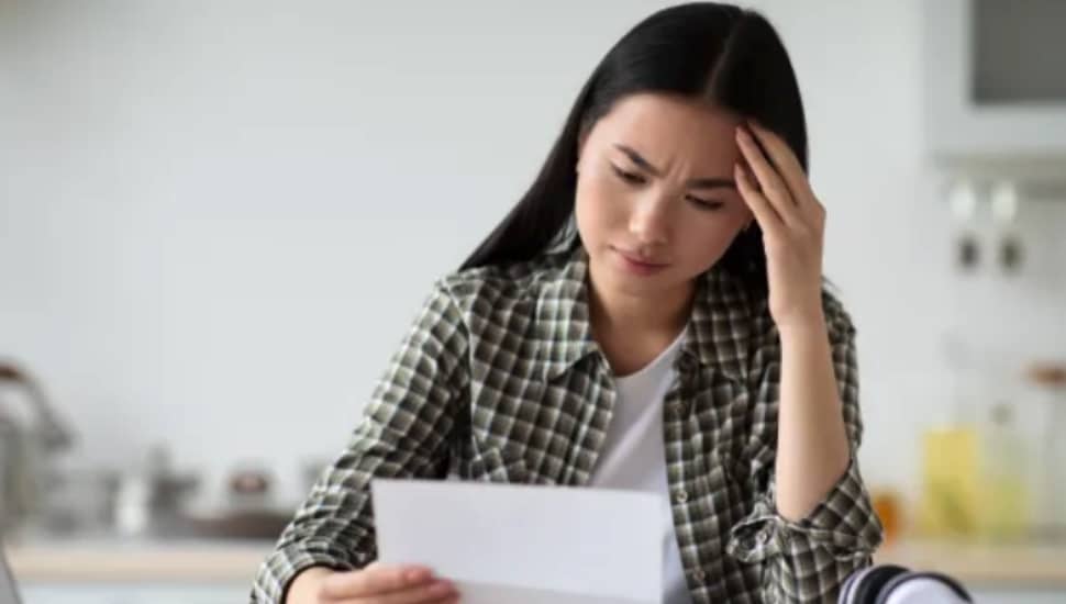 Stressed woman looking at shopping bill.