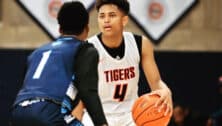 A high school basketball player dribbles while being guarded by an opposing player.