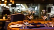 Two empty wine glasses sitting in a restaurant on a warm sunny afternoon.