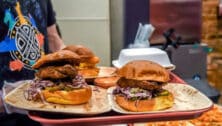 2 Crispy Fried Seitan, Grilled Scallion Slaw and House Bread & Butter Pickles on a Sweet Potato Bun from Algorithm Vegan Grill