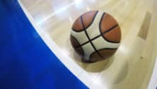 A basketball lay on the hardwood near the out-of-bounds-line