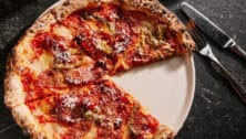 A pizza pie on a plate with a knife and fork