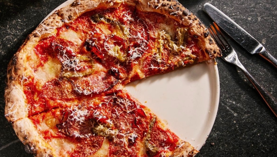 A pizza pie on a plate with a knife and fork