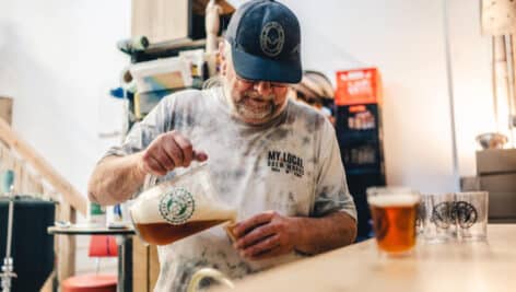 A man at My Local Brew Works pouring a beer into a glass.