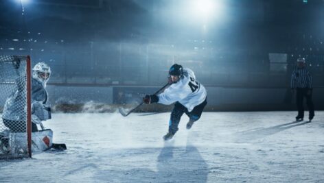 A goalie is on the defensive during an ice hockey game in an ice rink.