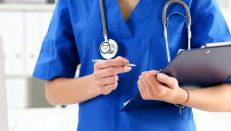 close up of a medical worker in scrubs with a clip board.