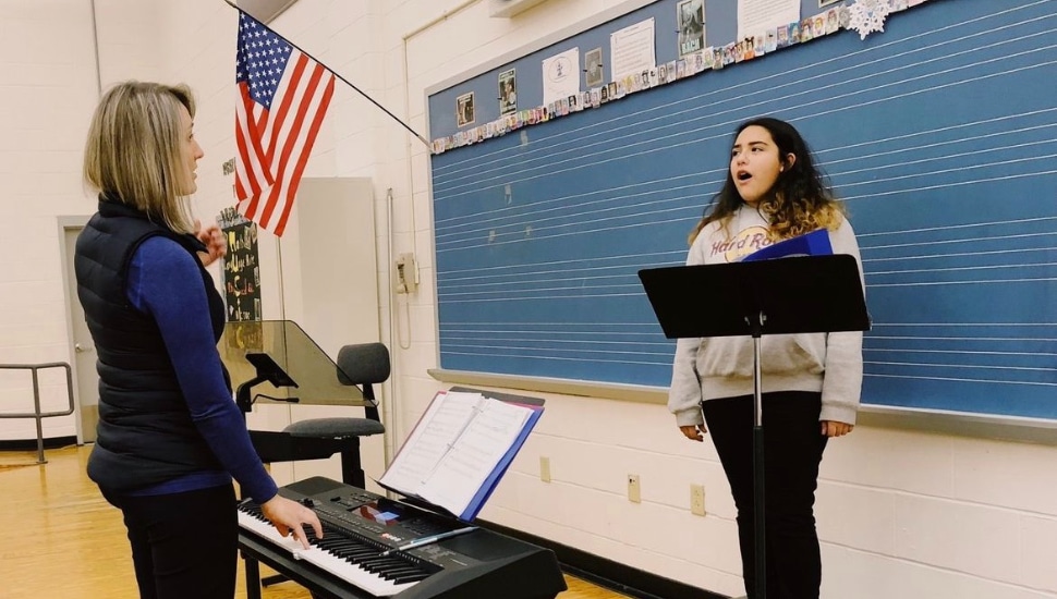 A young girl singing with instructor.