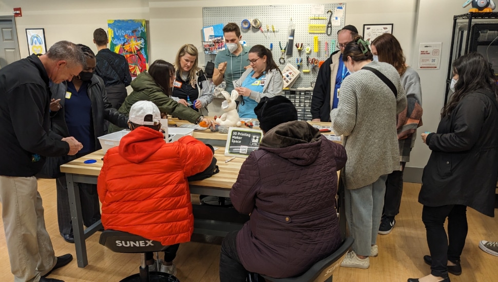 Guests gather around tables to work with 3D printed switches inside TechOWL.