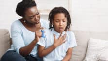 A mother holding asthma inhaler for her young daughter.