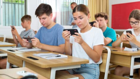 Students sitting in class on their cellphone.