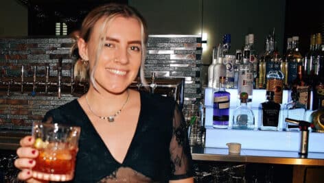 Female mixology holds drink at a bar.