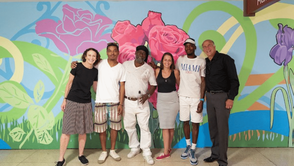 Jane Golden gathered with a group in front of a mural that is part of the Color me Back City of Philadelphia Mural Arts Program.