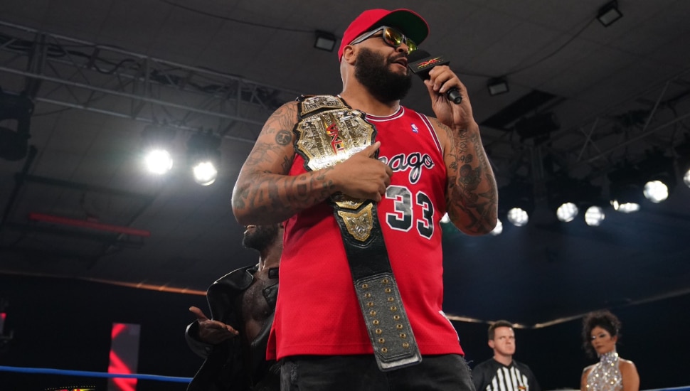 AJ Francis on the mic while in the ring holding his Digital Media Championships on his shoulder.