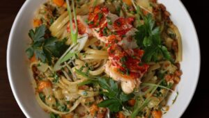 overhead photo of pasta dish topped with protein and leaves