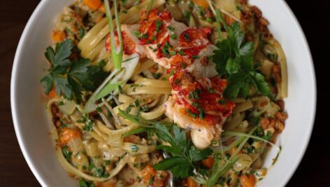 overhead photo of pasta dish topped with protein and leaves