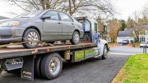 A tow truck taking a car away after it was illegally parked.