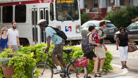 People riding bikes and walking in Philadelphia. A SEPTA bus is also in the background.