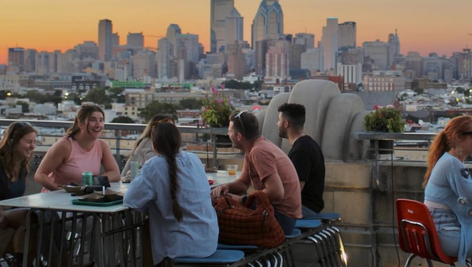 People enjoying drink at Bok Bar with city skyline in the background.