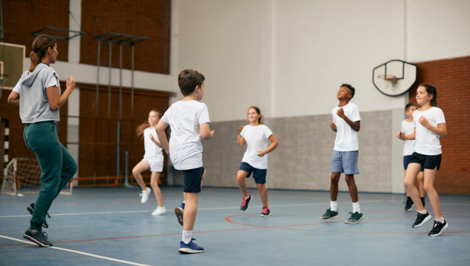 Kids inside a gym doing activities with instructor.